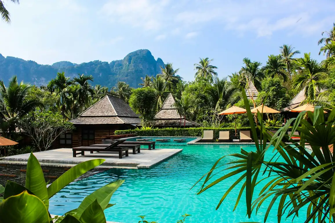 Tropical resort pool surrounded by thatched villas