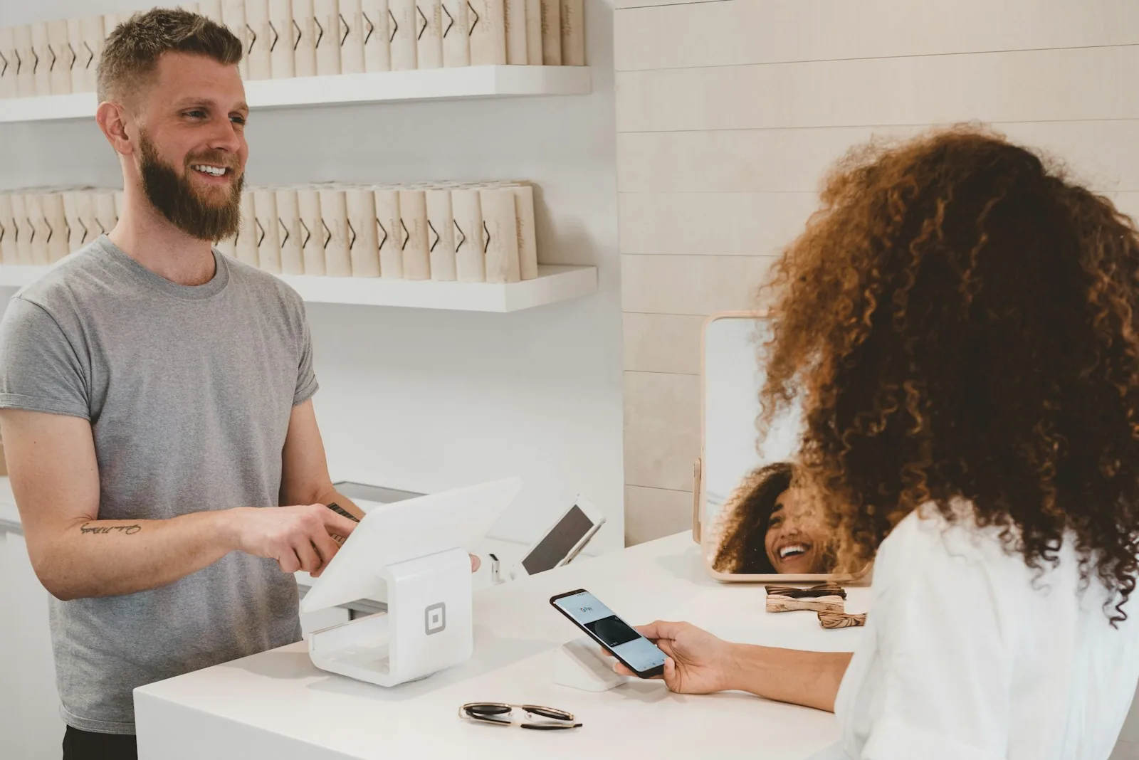 Shop owner serving a customer who pays by phone