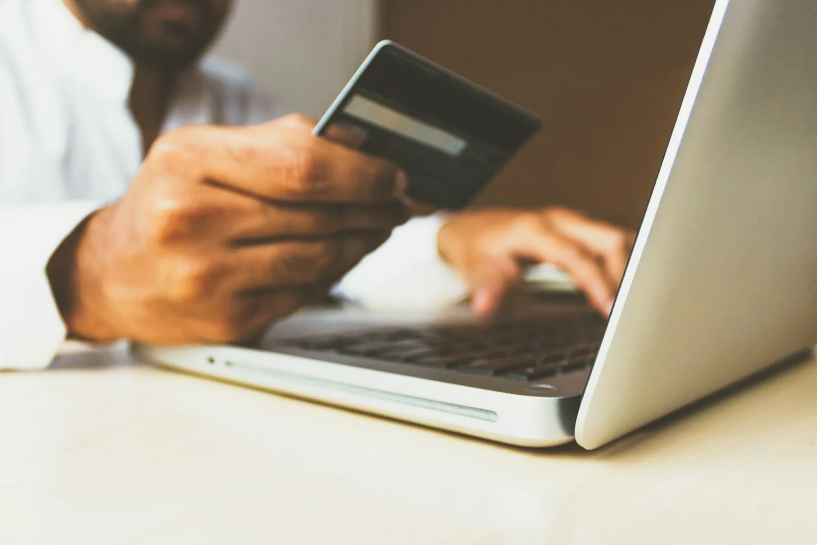 Hand holding a bank card at a laptop