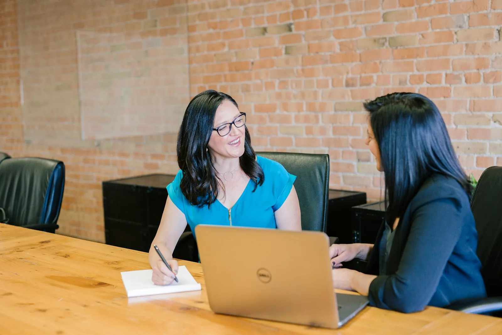 Two women talking across a laptop at a table