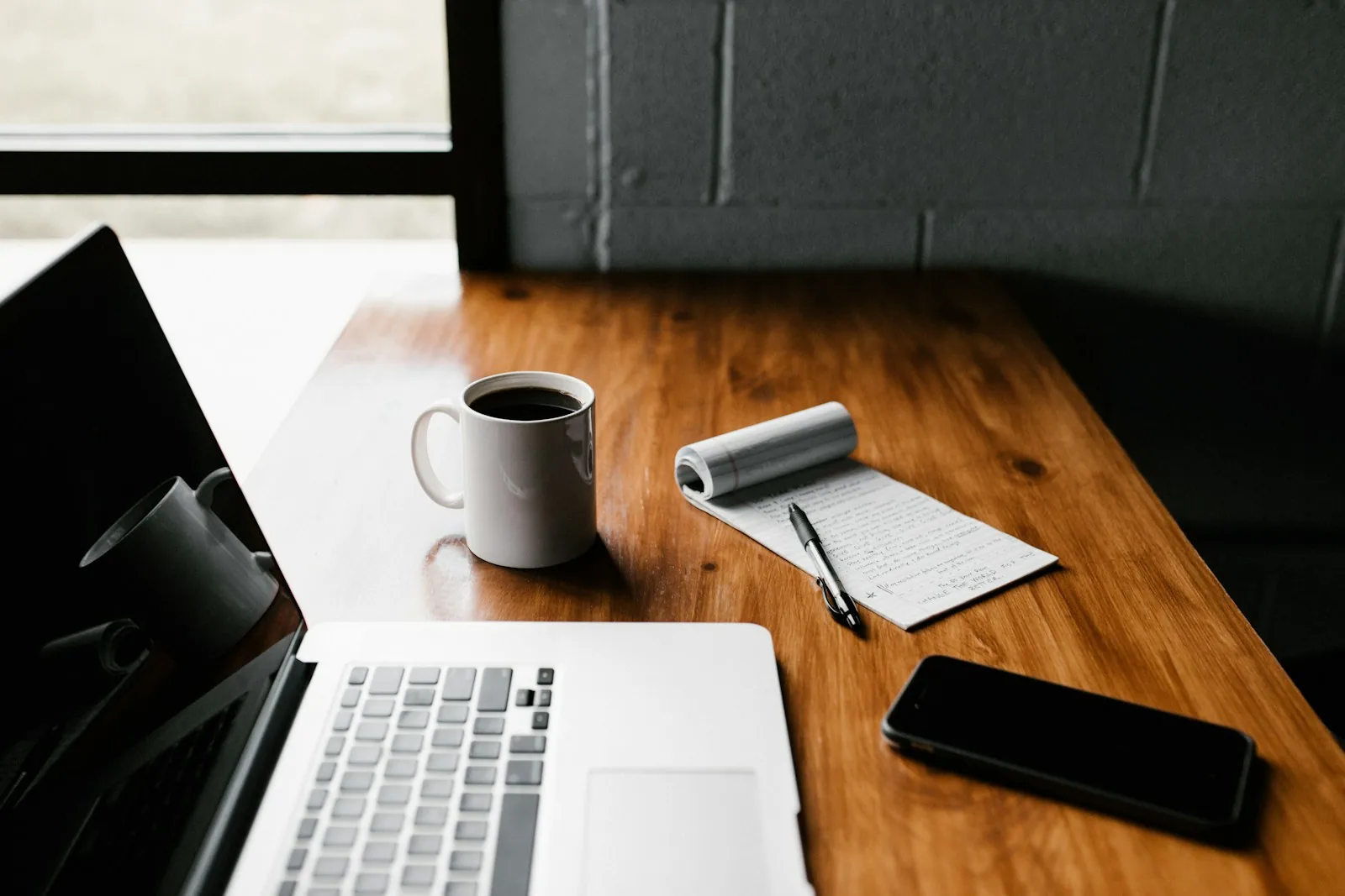Laptop, coffee and notepad on a wooden desk