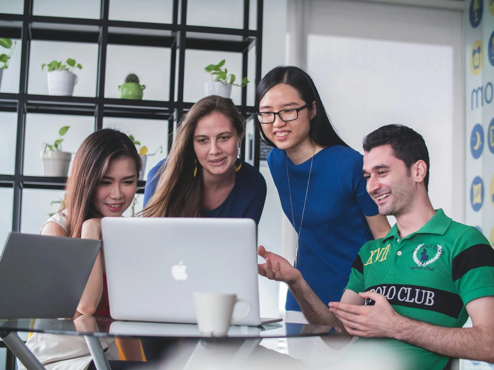 Four colleagues smiling at a laptop